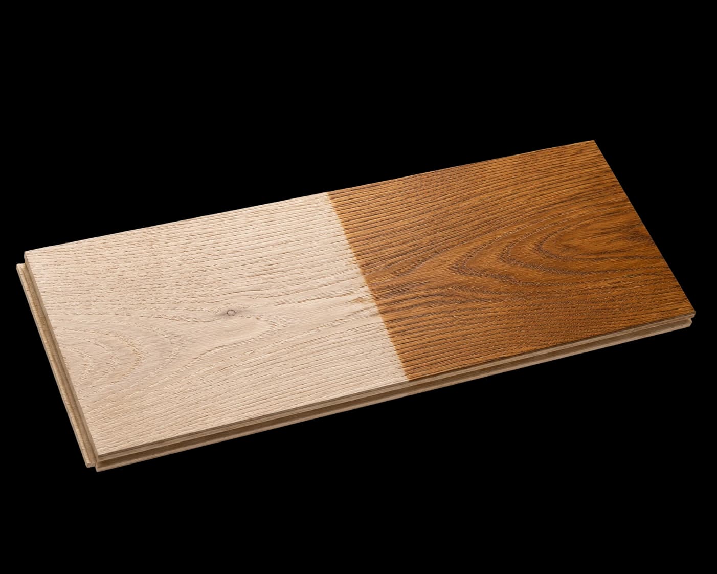 A single wide hardwood plank, raw white oak on one half and hand-finished amber on the other