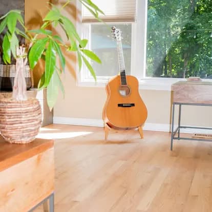 Pale natural maple floor in a bright Harbor Springs room, a guitar by the window